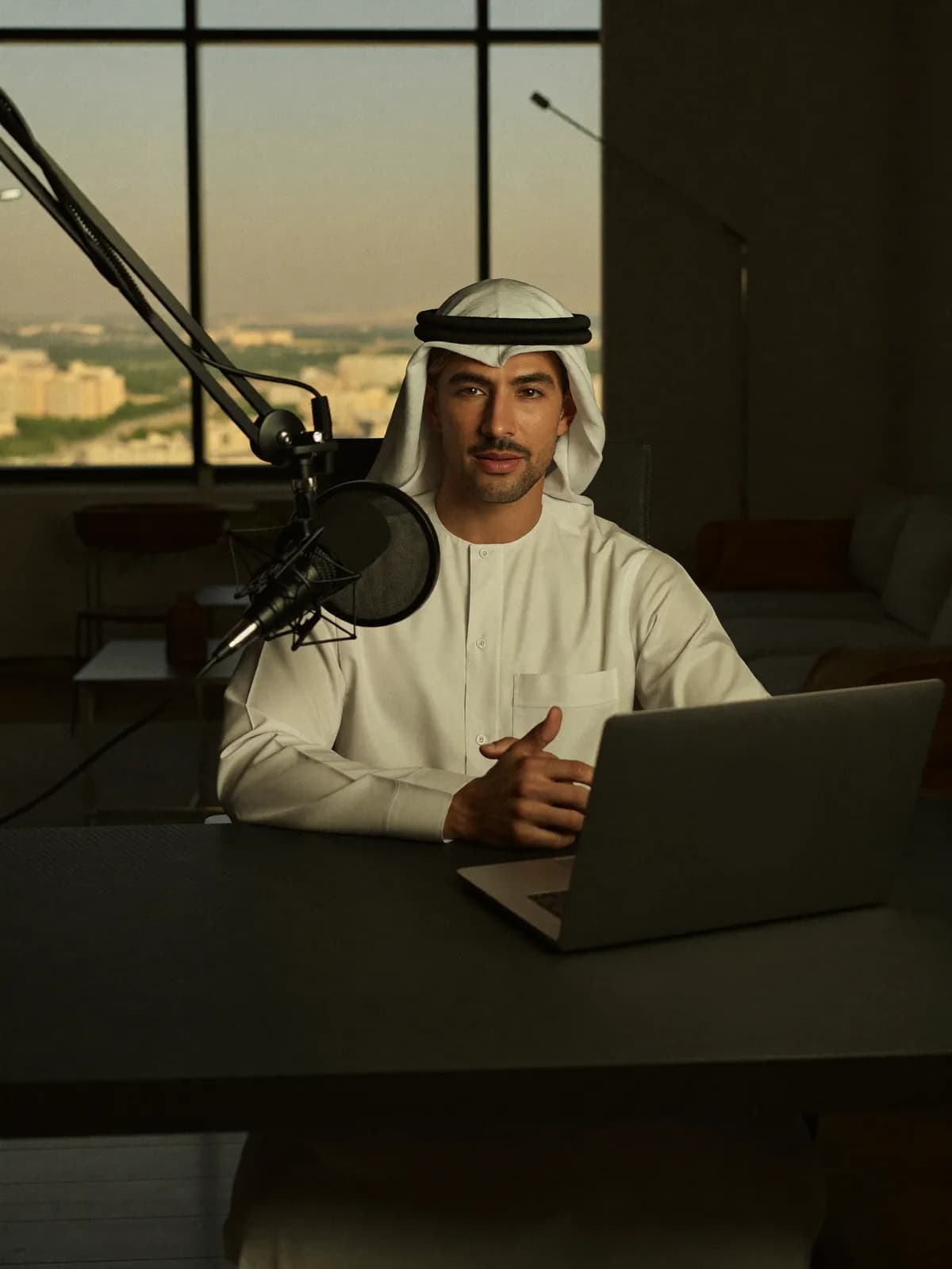 صانع محتوى خليجي يسجّل حلقة بودكاست أمام الميكروفون والحاسوب